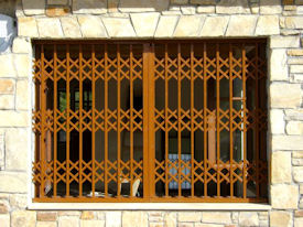 Rejas de seguridad plegables con láminas dobles de acero de Viometaloumin en una casa de piedra.